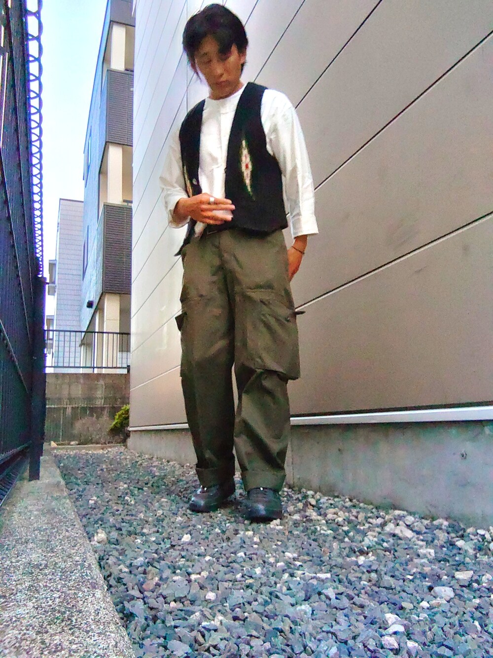 ブラック系のベスト、ホワイト系のシャツ/ブラウス、グリーン系のカーゴパンツを着用したメンズの春コーディネートの2枚目の写真