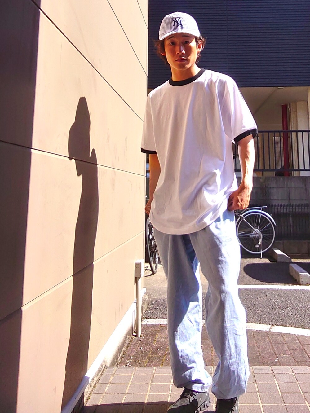 ホワイト系のTシャツ/カットソー、ブルー系のパンツ、ブラック系のスニーカーを着用したメンズの夏コーディネートの2枚目の写真