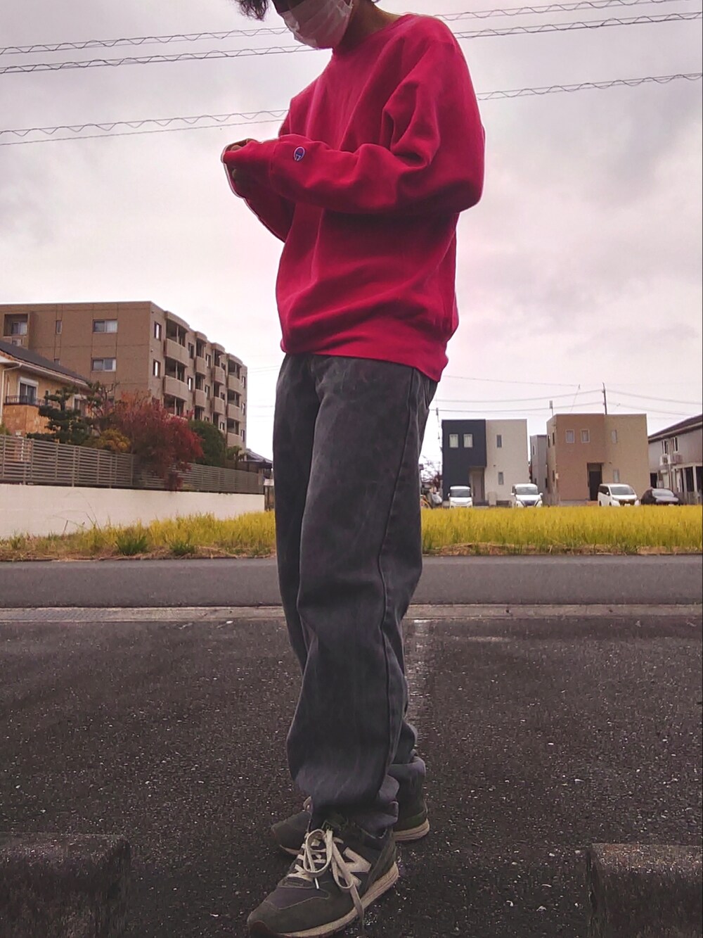 レッド系のスウェット、グレー系のデニムパンツ、ブルー系のスニーカーを着用したメンズの秋コーディネートの2枚目の写真