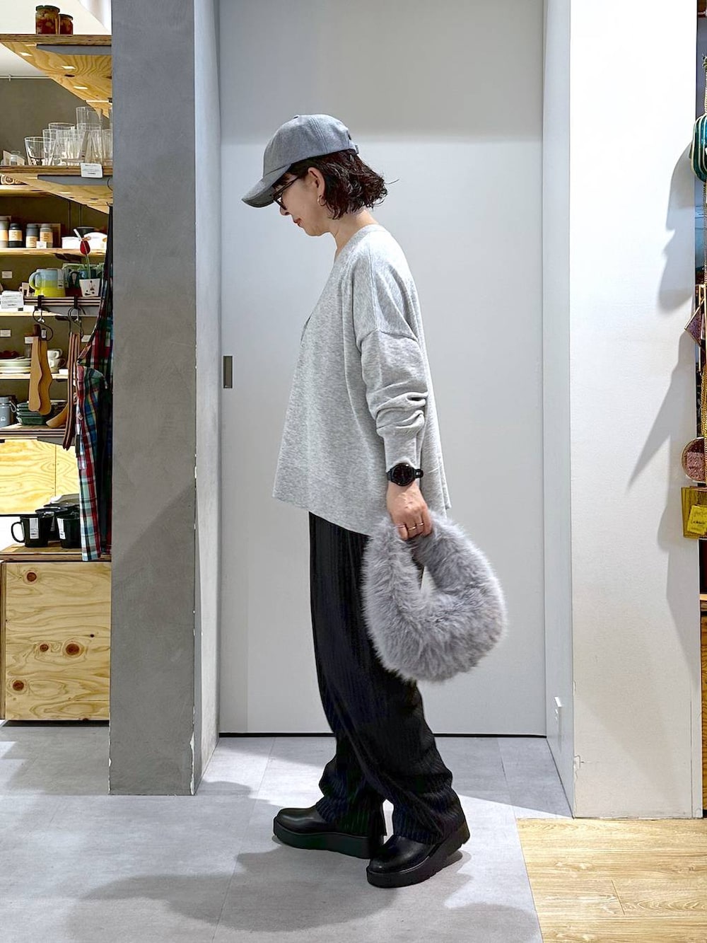 グレー系のハンドバッグ、ブラック系のブーツ、グレー系のカーディガン/ボレロを着用したレディースの秋コーディネートの2枚目の写真