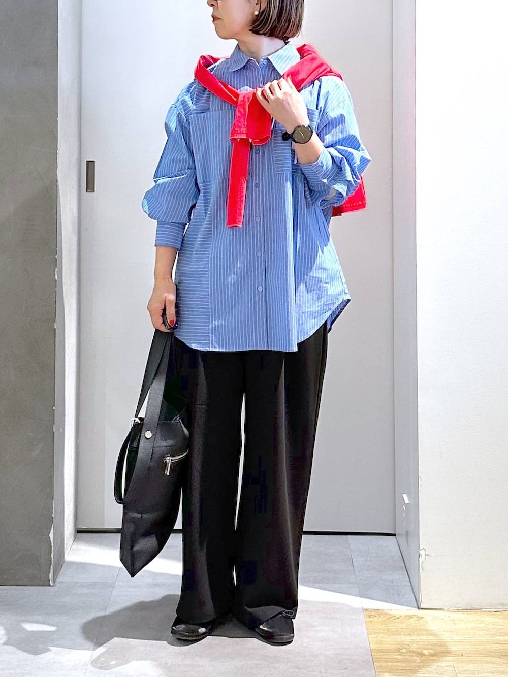 ブラック系のトートバッグ、ブラック系のスラックス、ブルー系のシャツ/ブラウスを着用したレディースの春コーディネートの3枚目の写真