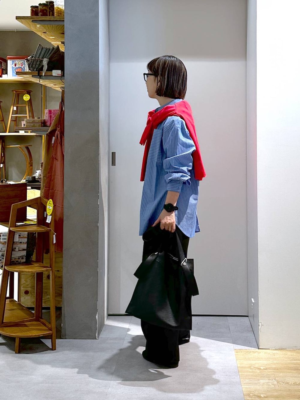 ブラック系のトートバッグ、ブラック系のスラックス、ブルー系のシャツ/ブラウスを着用したレディースの春コーディネートの2枚目の写真