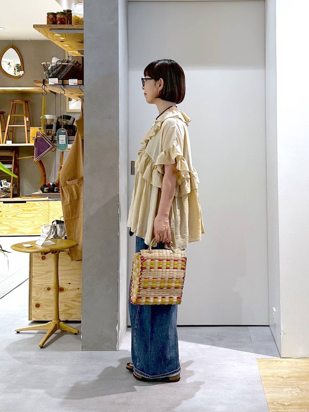 ブルー系のデニムパンツ、ベージュ系のシャツ/ブラウス、イエロー系のかごバッグを着用したレディースの夏コーディネートの3枚目の写真