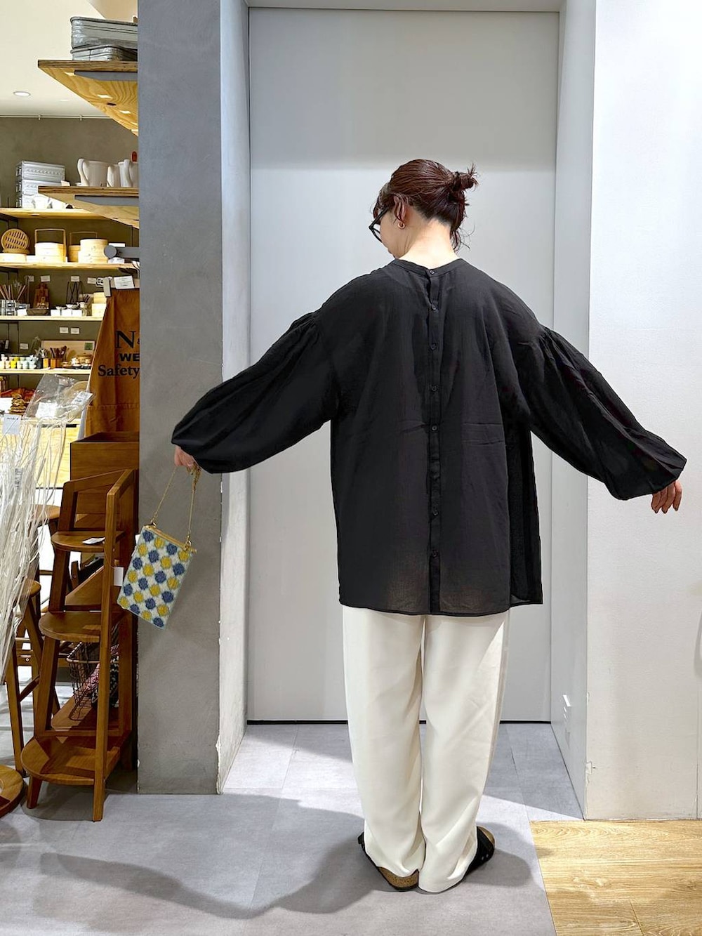 ブルー系のショルダーバッグ、ベージュ系のスラックスを着用したレディースの夏コーディネートの3枚目の写真