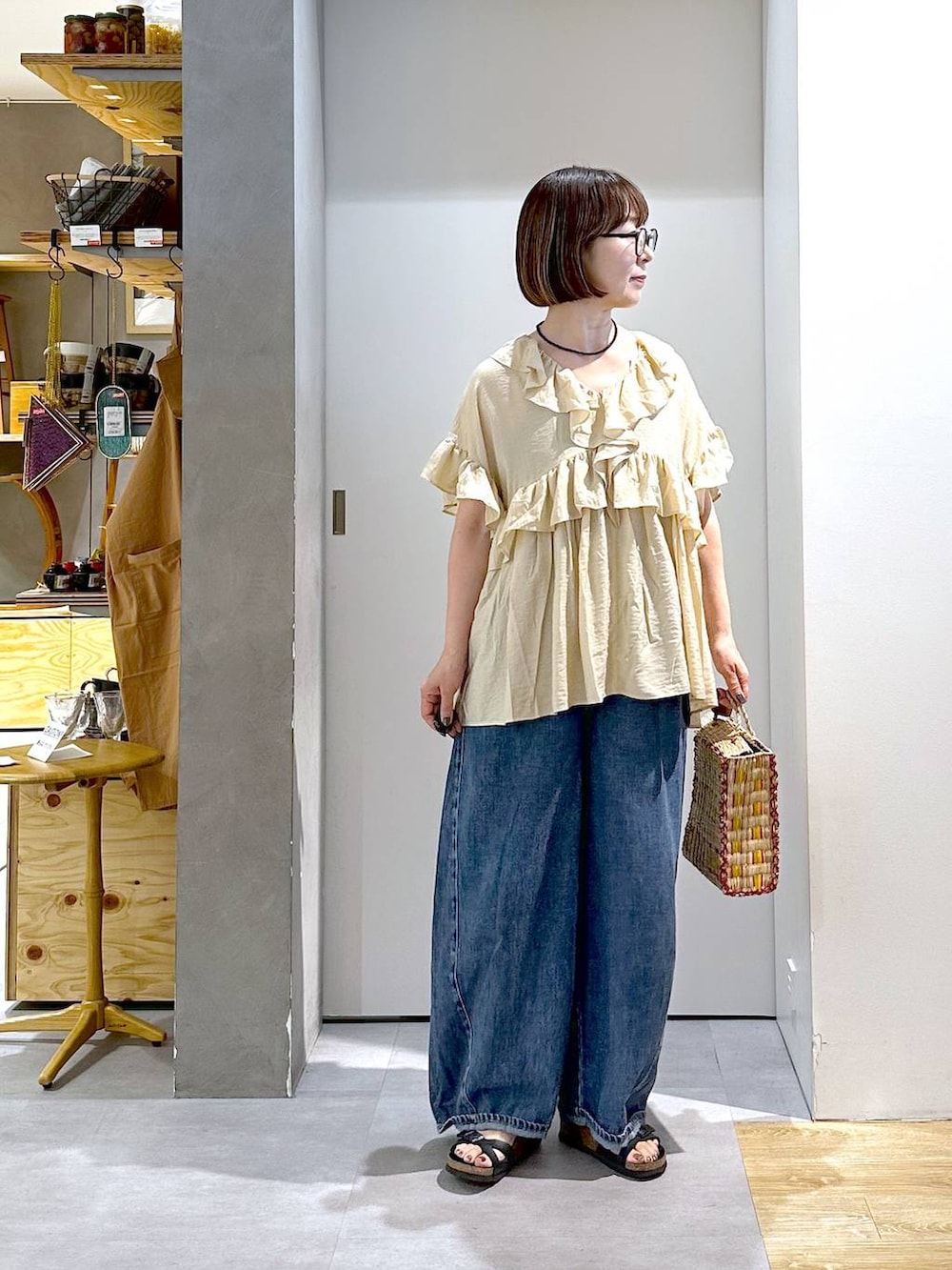 ブルー系のデニムパンツ、ベージュ系のシャツ/ブラウス、イエロー系のかごバッグを着用したレディースの夏コーディネートの4枚目の写真
