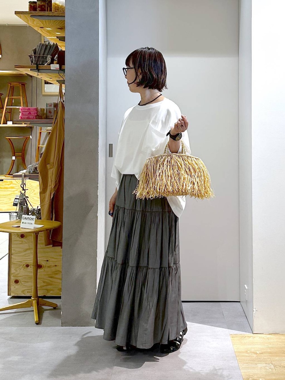 グレー系のスカート、ホワイト系のTシャツ/カットソー、ベージュ系のハンドバッグを着用したレディースの春コーディネートの2枚目の写真