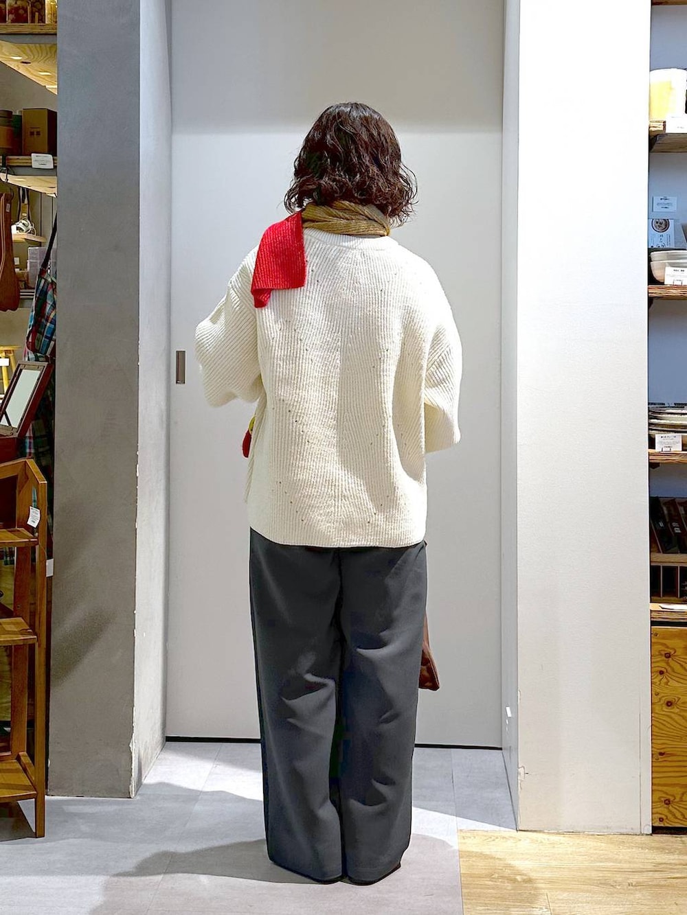 ホワイト系のニット/セーター、ブラウン系のエコバッグ/サブバッグ、グレー系のスラックスを着用したレディースの冬コーディネートの3枚目の写真