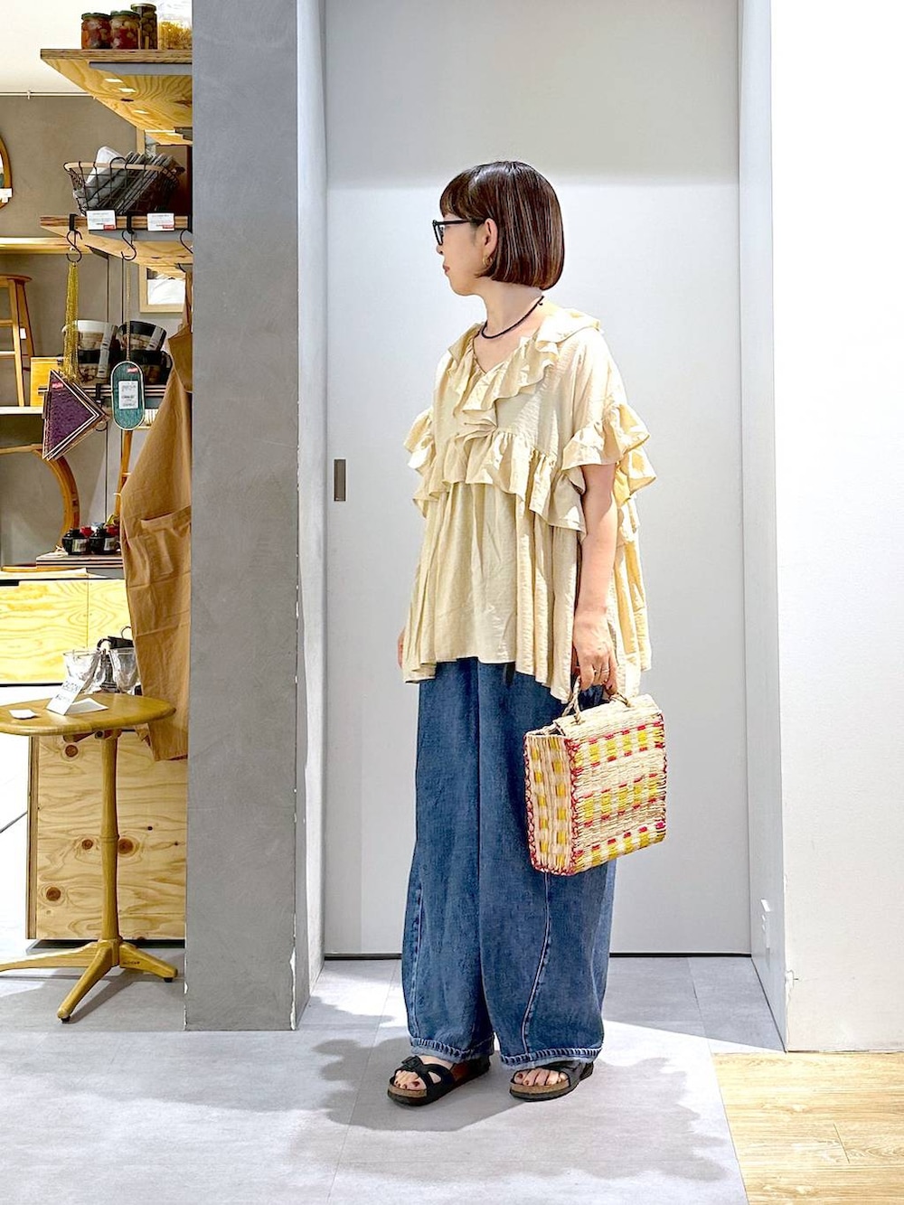 ブルー系のデニムパンツ、ベージュ系のシャツ/ブラウス、イエロー系のかごバッグを着用したレディースの夏コーディネートの2枚目の写真