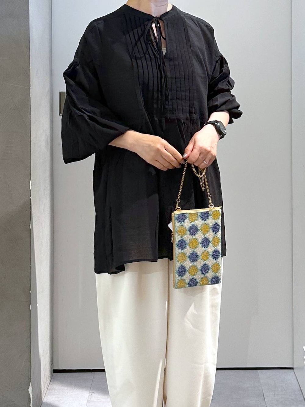 ブルー系のショルダーバッグ、ベージュ系のスラックスを着用したレディースの夏コーディネートの5枚目の写真