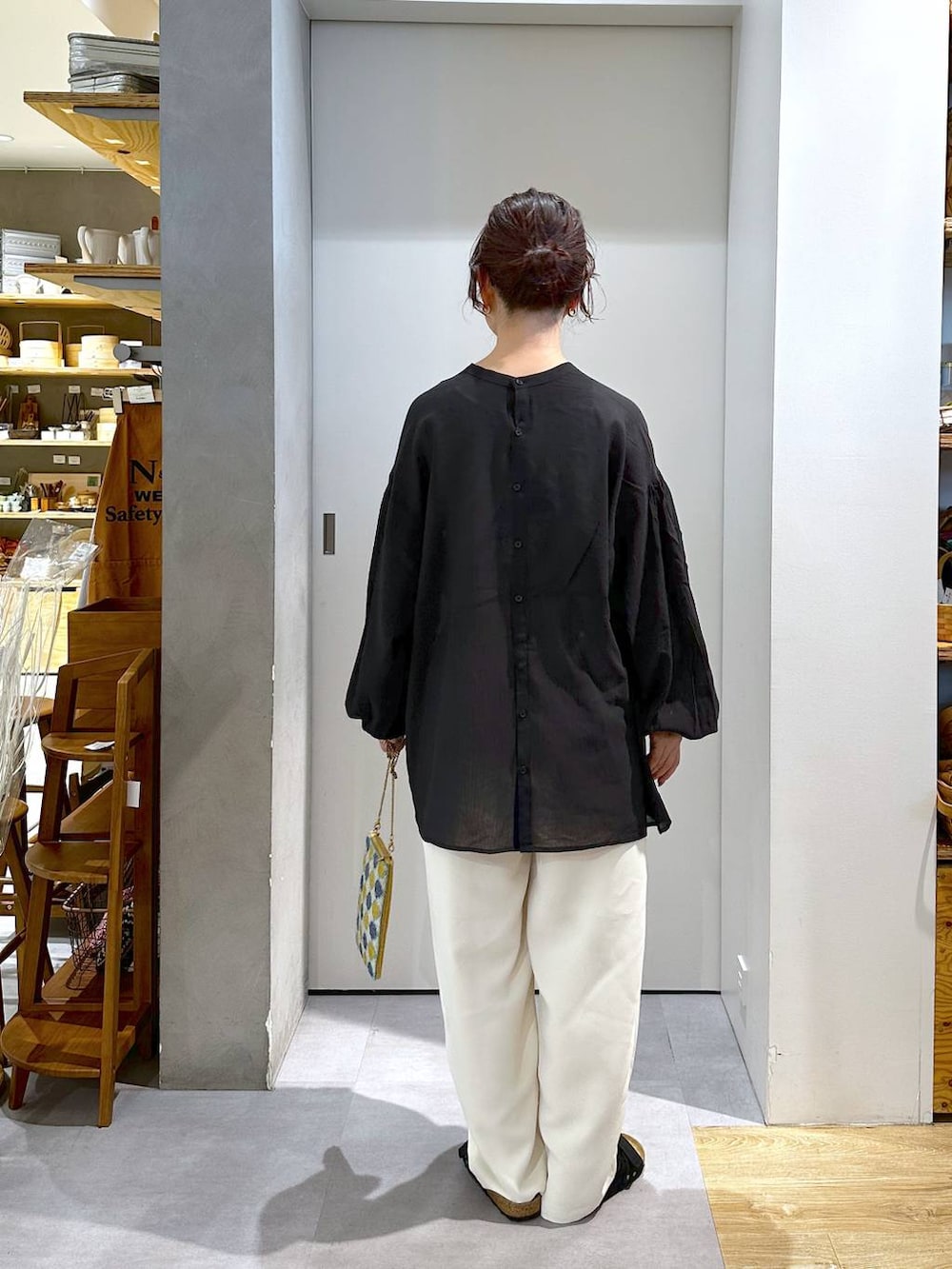 ブルー系のショルダーバッグ、ベージュ系のスラックスを着用したレディースの夏コーディネートの2枚目の写真