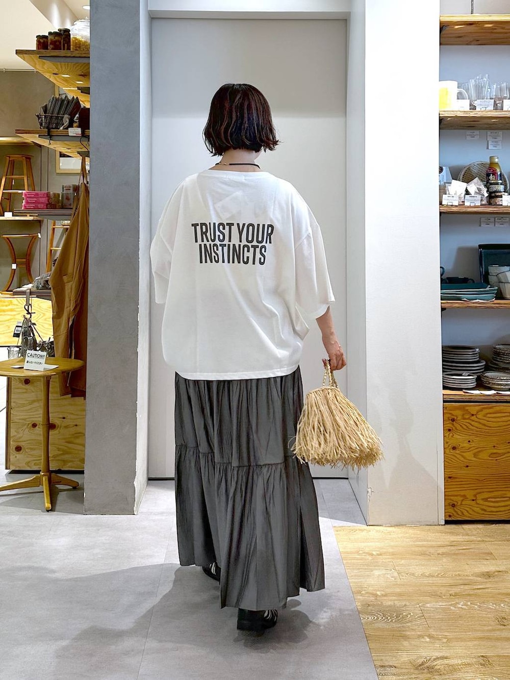 グレー系のスカート、ホワイト系のTシャツ/カットソー、ベージュ系のハンドバッグを着用したレディースの春コーディネートの3枚目の写真
