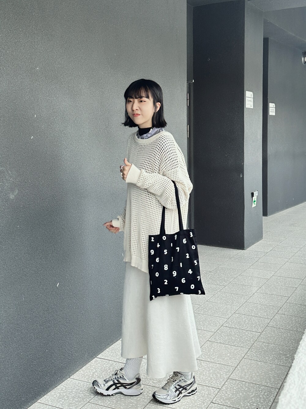 ベージュ系のニット/セーター、シルバー系のスニーカー、ブラック系のトートバッグを着用したレディースの秋コーディネートの2枚目の写真