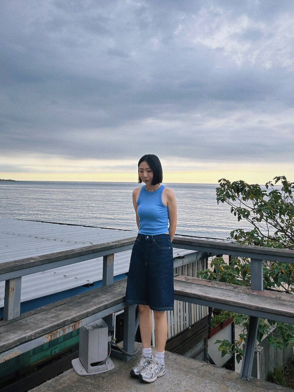 ブルー系のタンクトップ、ブルー系のカーゴパンツ、シルバー系のスニーカーを着用したレディースの夏コーディネートの2枚目の写真