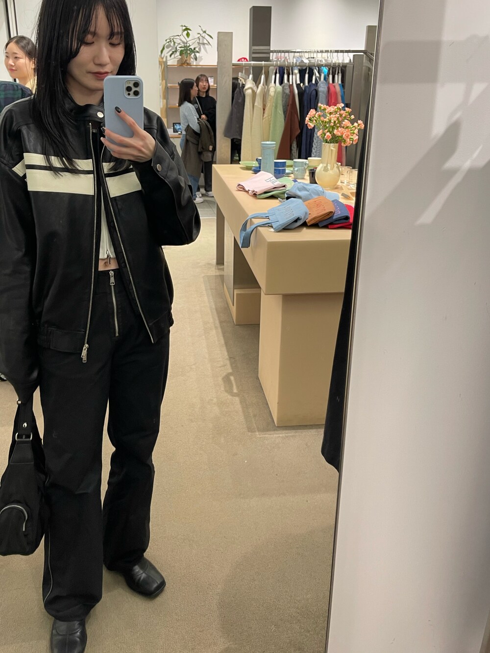 ホワイト系のトップス、ブラック系のライダースジャケット、ブラック系のカーゴパンツを着用したレディースの春コーディネートの2枚目の写真