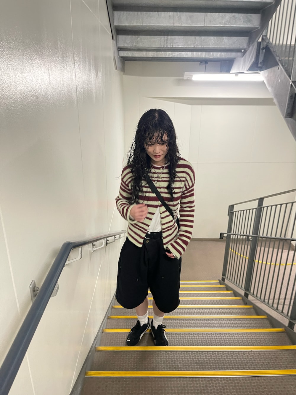 ブラック系のチノパンツ、その他のカーディガン/ボレロ、ブラック系のスニーカーを着用したレディースの秋コーディネートの2枚目の写真