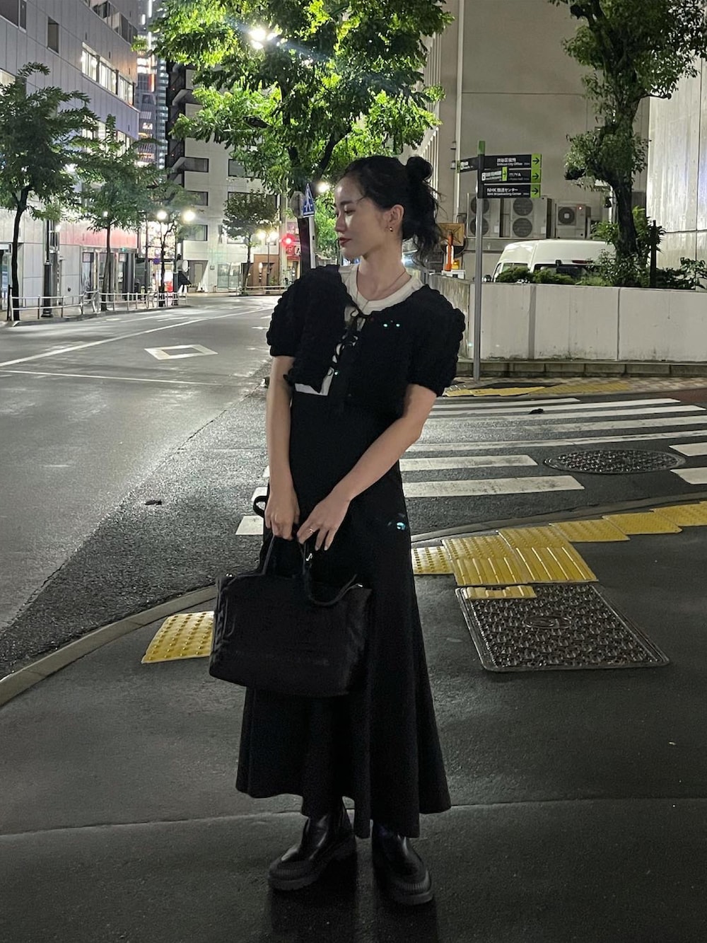 ブラック系のスカート、ブラック系のブーツ、ブラック系のハンドバッグを着用したレディースの秋コーディネートの2枚目の写真