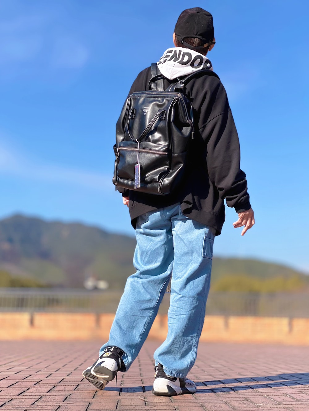 ブラック系のバックパック/リュック、ブラック系のパーカー、ホワイト系のパーカーを着用したメンズの冬コーディネートの3枚目の写真