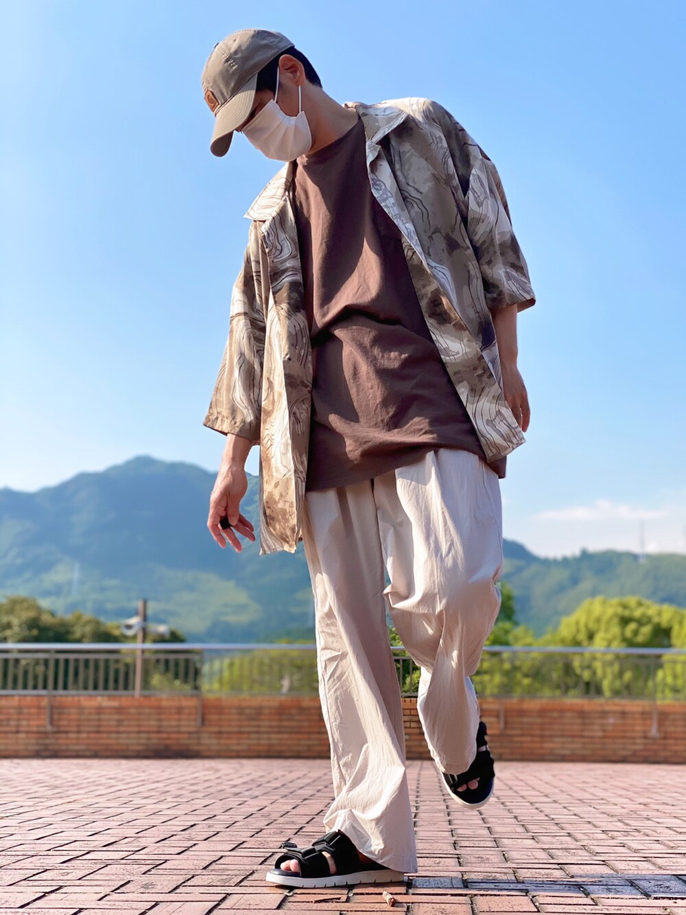 ブラウン系のTシャツ/カットソー、グレー系のその他パンツ、ブラック系のサンダルを着用したメンズの夏コーディネートの2枚目の写真