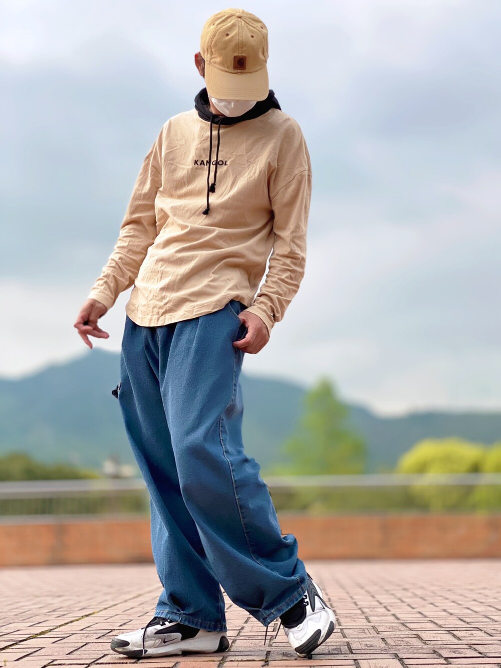 ベージュ系のパーカー、ブルー系のデニムパンツ、ホワイト系のスニーカーを着用したメンズの春コーディネートの2枚目の写真