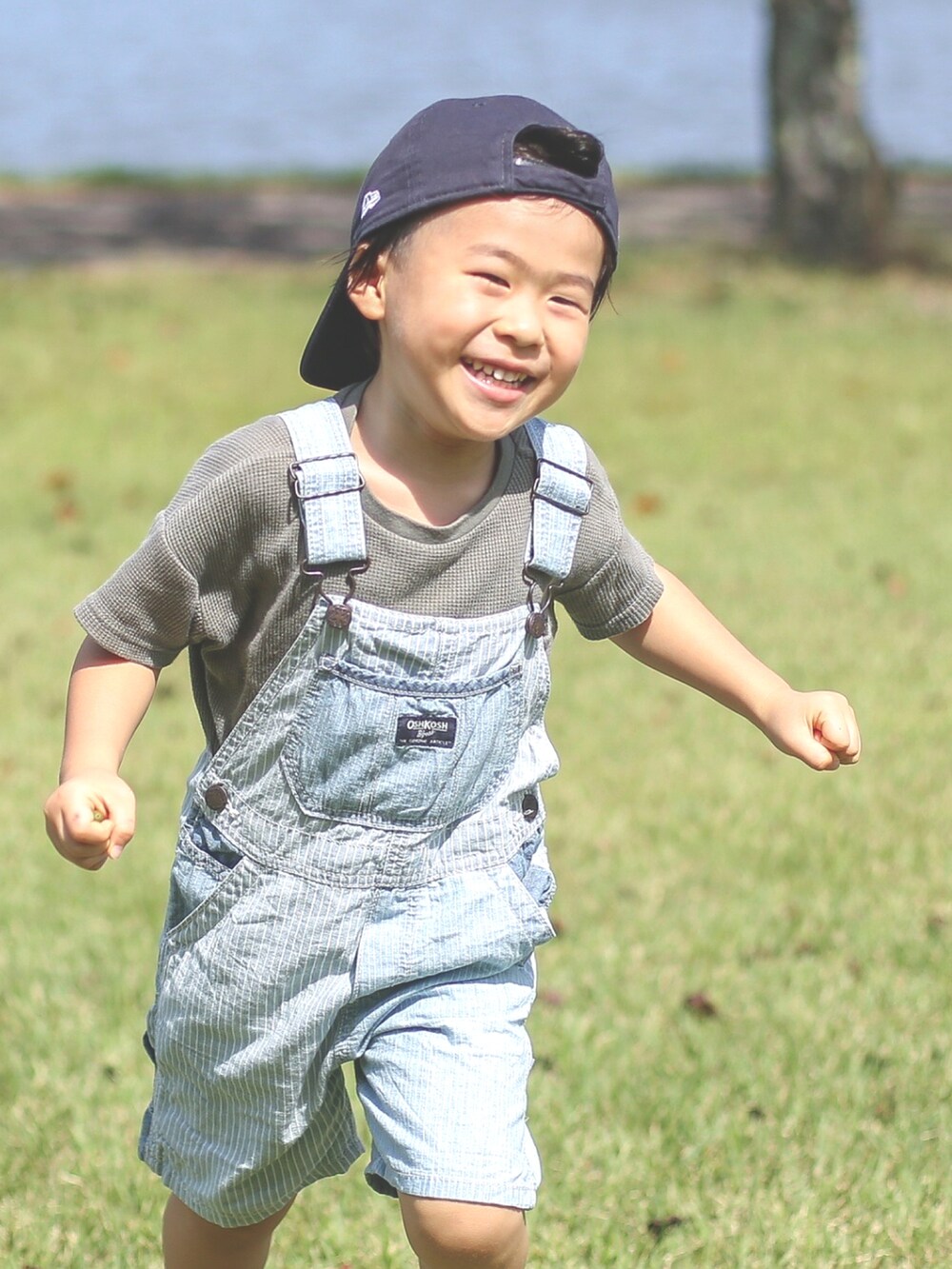 ブルー系のサロペット/オーバーオール、ベージュ系のスニーカー、ブルー系のキャップを着用したキッズの秋コーディネートの2枚目の写真