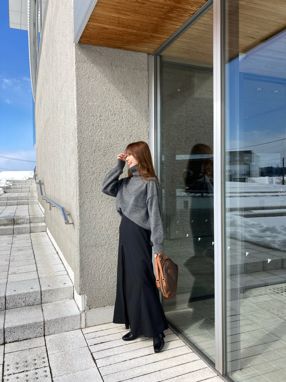 ブラック系のスカート、グレー系のニット/セーター、ブラウン系のバッグを着用したレディースの冬コーディネートの2枚目の写真