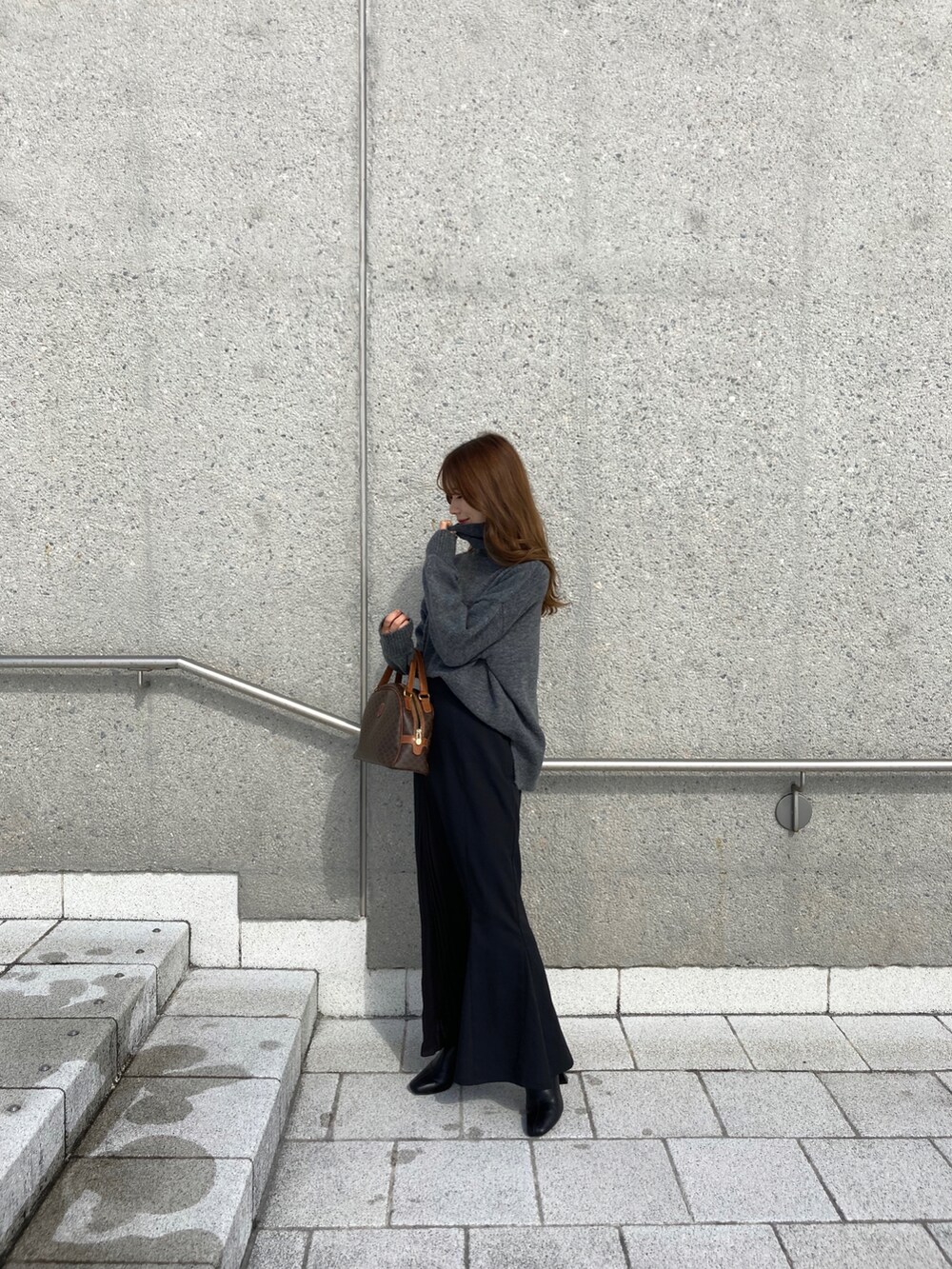 ブラック系のスカート、グレー系のニット/セーター、ブラウン系のバッグを着用したレディースの冬コーディネートの3枚目の写真