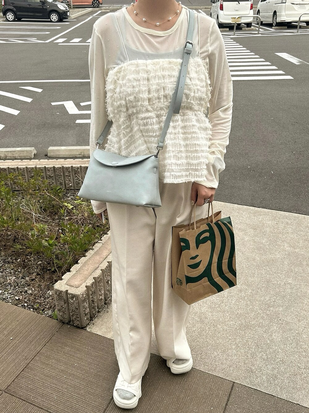 ホワイト系のスラックス、ホワイト系のキャミソール、ブルー系のショルダーバッグを着用したレディースの春コーディネートの4枚目の写真