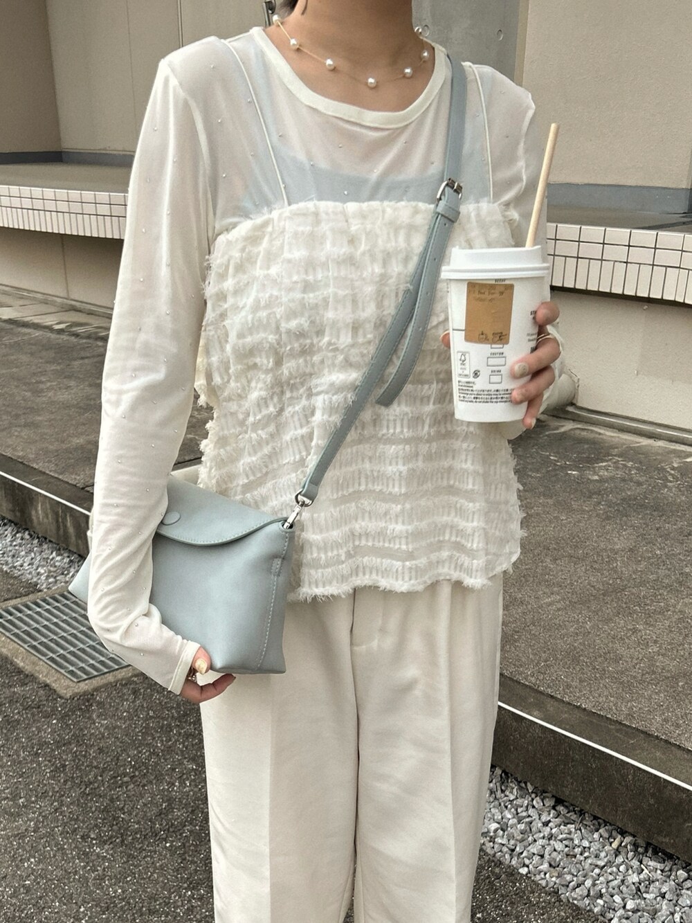 ホワイト系のスラックス、ホワイト系のキャミソール、ブルー系のショルダーバッグを着用したレディースの春コーディネートの3枚目の写真