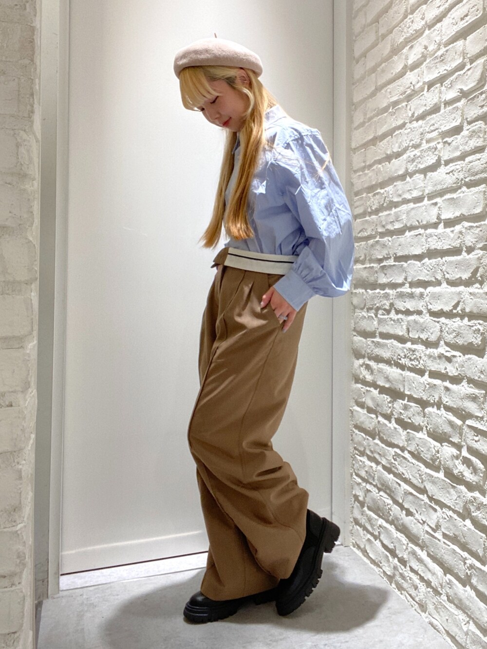 ベージュ系のスラックス、ブルー系のシャツ/ブラウス、ブラック系のブーツを着用したレディースの秋コーディネートの2枚目の写真