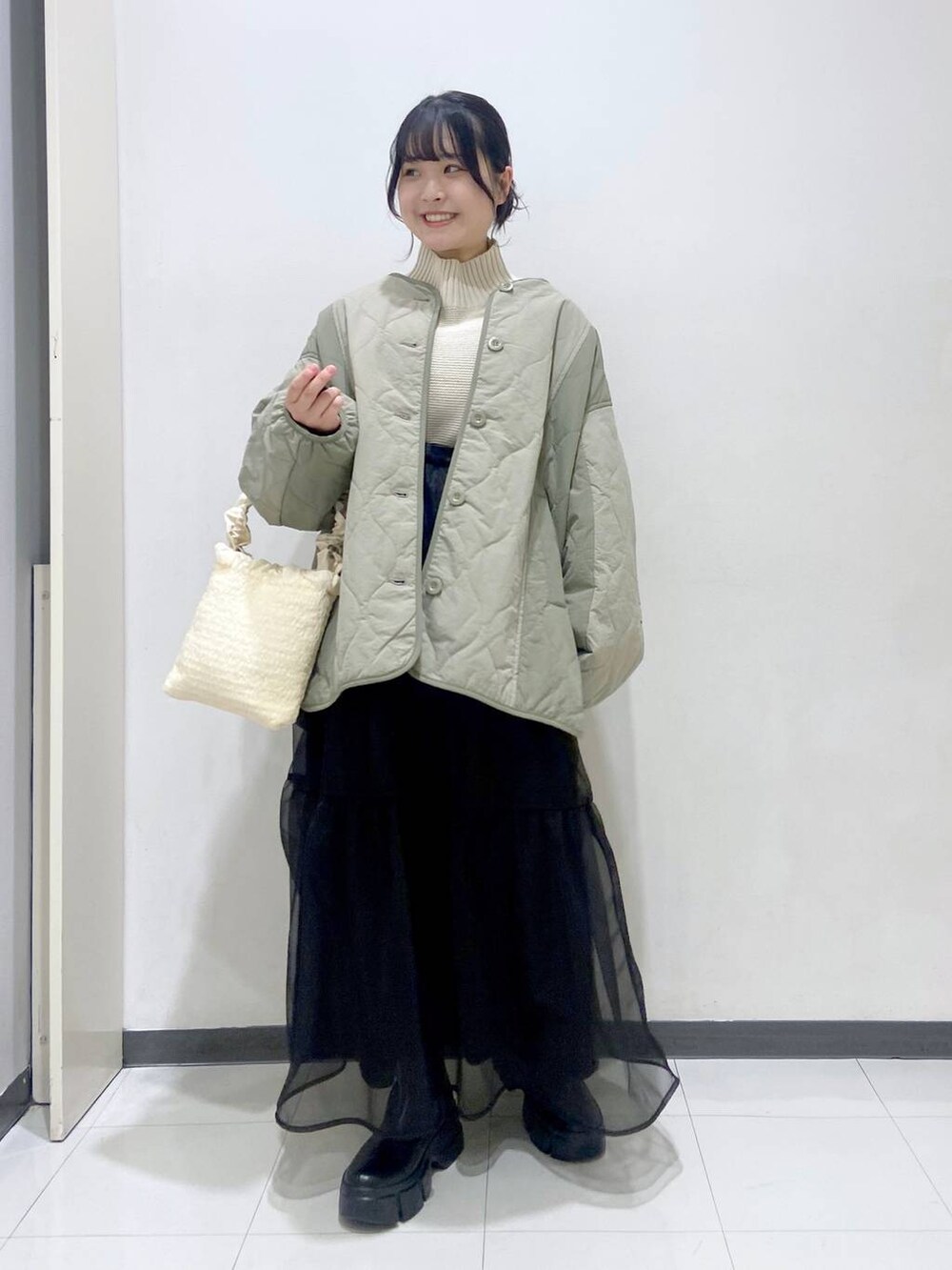 ホワイト系のニット/セーター、グリーン系のブルゾン、ホワイト系のショルダーバッグを着用したレディースの冬コーディネートの2枚目の写真