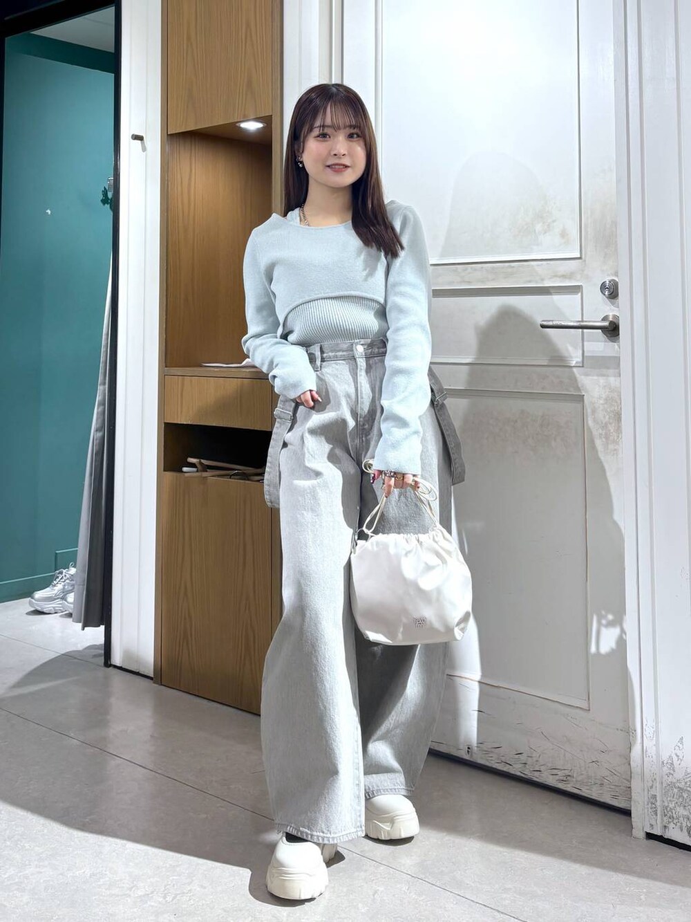 グレー系のデニムパンツ、ホワイト系のショルダーバッグ、グリーン系のニット/セーターを着用したレディースの春コーディネートの3枚目の写真