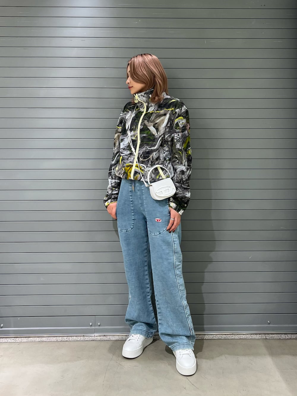 ブラック系のナイロンジャケット、ホワイト系のショルダーバッグ、ブルー系のデニムパンツを着用したレディースの春コーディネートの2枚目の写真