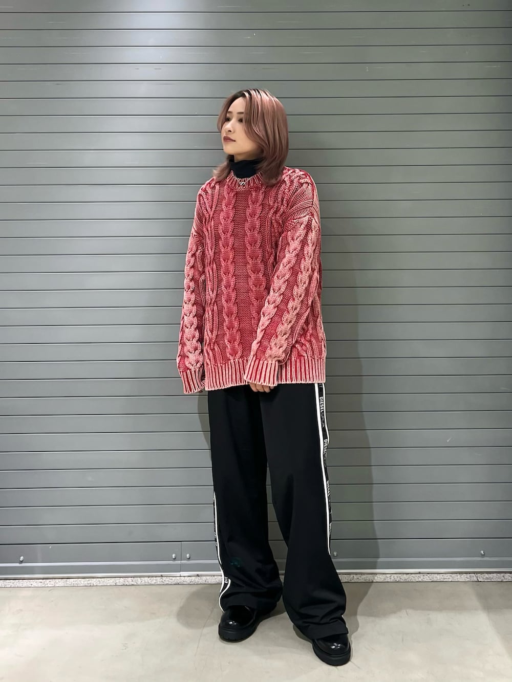 レッド系のニット/セーター、ブラック系のスウェットパンツ、ブラック系のブーツを着用したレディースの冬コーディネートの2枚目の写真