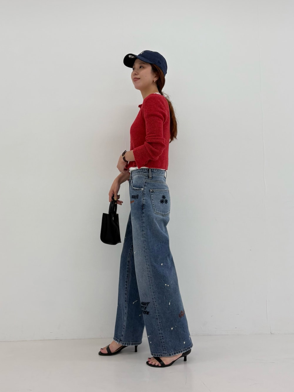 ブルー系のデニムパンツ、ホワイト系のTシャツ/カットソー、ブラック系のハンドバッグを着用したレディースの夏コーディネートの3枚目の写真