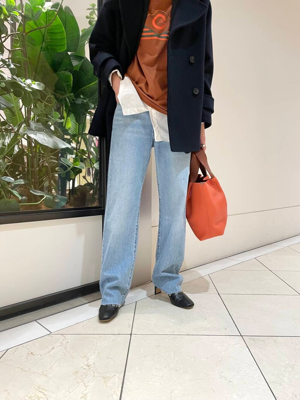 ブルー系のピーコート、ブルー系のデニムパンツ、ブラック系のブーツを着用したレディースの冬コーディネートの7枚目の写真