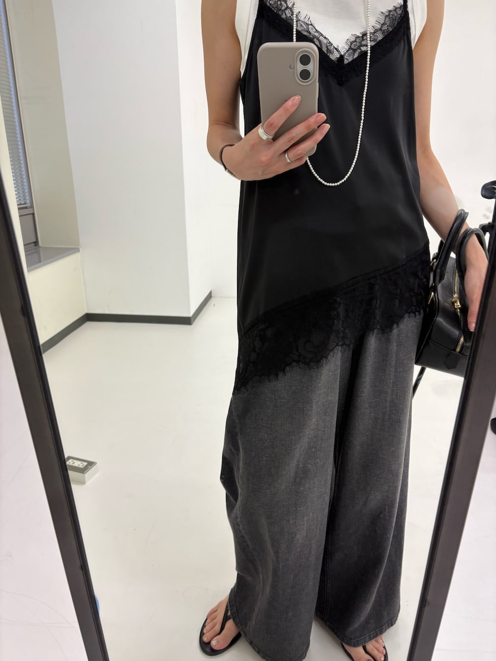 ブラック系のキャミソール、ホワイト系のタンクトップ、ブラック系のデニムパンツを着用したレディースの夏コーディネートの8枚目の写真