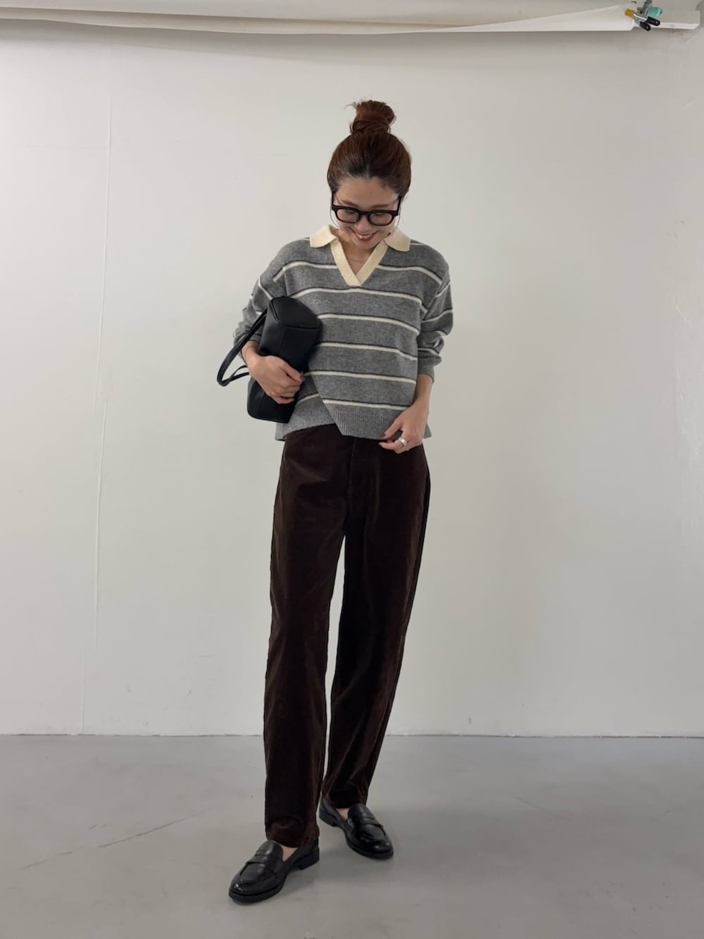 グレー系のニット/セーター、ブラウン系のその他パンツ、ブラック系のハンドバッグを着用したレディースの秋コーディネートの5枚目の写真