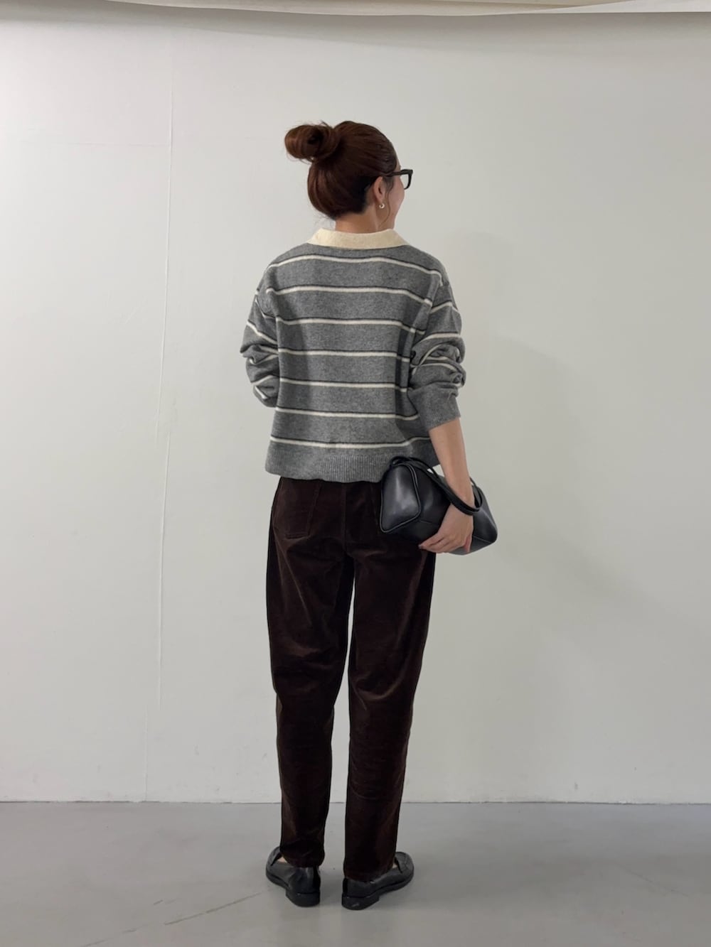 グレー系のニット/セーター、ブラウン系のその他パンツ、ブラック系のハンドバッグを着用したレディースの秋コーディネートの3枚目の写真