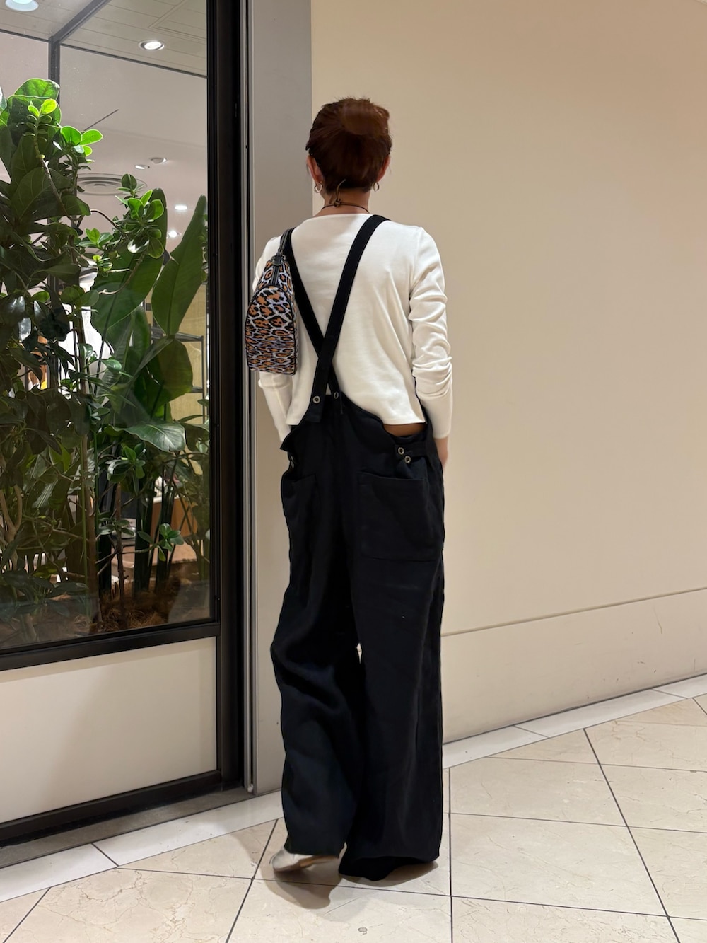 ブラック系のサロペット/オーバーオール、ホワイト系のTシャツ/カットソー、パープル系のハンドバッグを着用したレディースの春コーディネートの4枚目の写真