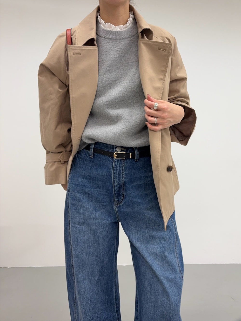 ベージュ系のトレンチコート、ブルー系のデニムパンツ、オレンジ系のショルダーバッグを着用したレディースの冬コーディネートの6枚目の写真