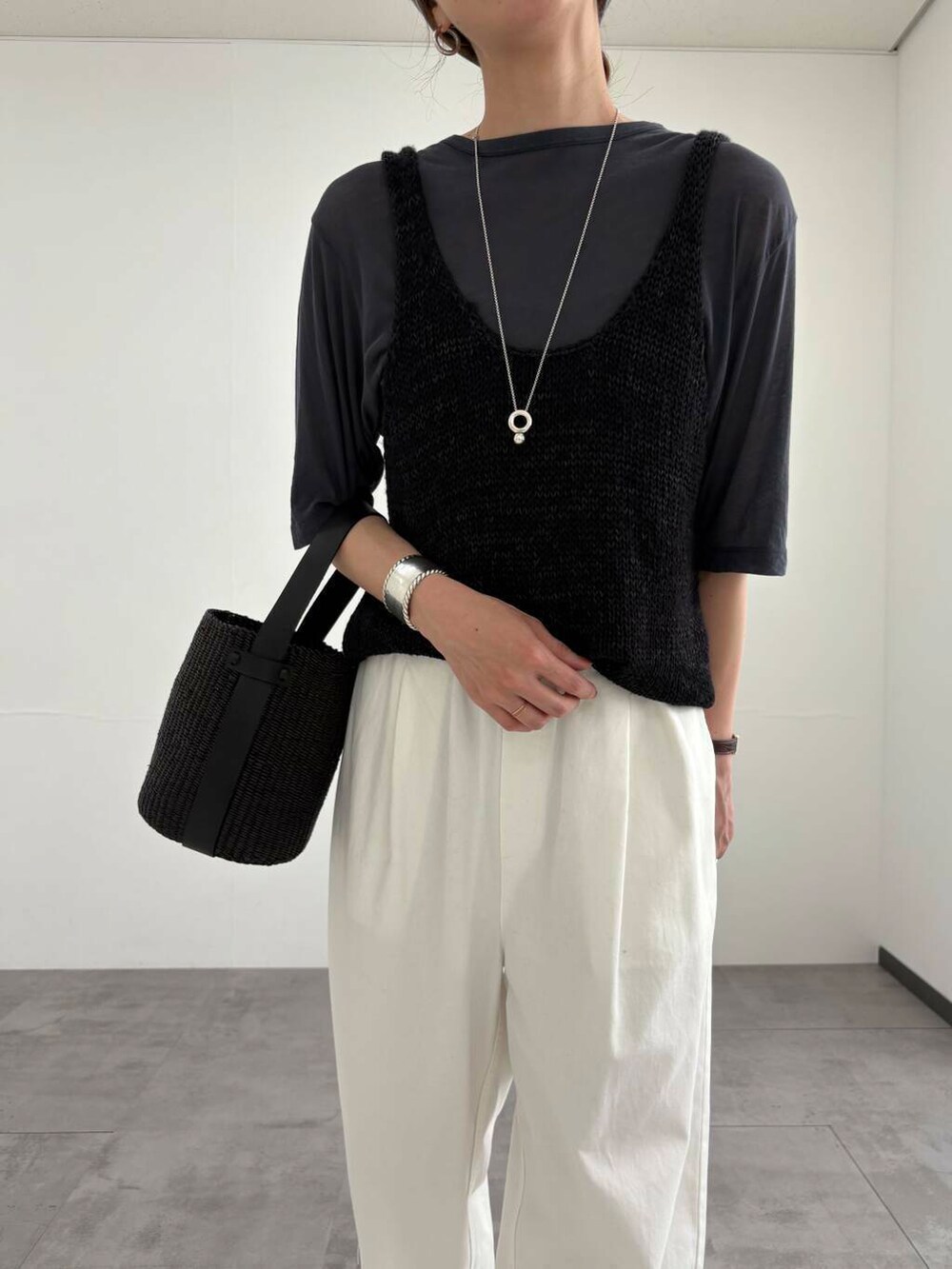 ブラック系のかごバッグ、ホワイト系のその他パンツ、ブラック系のサンダルを着用したレディースの夏コーディネートの7枚目の写真