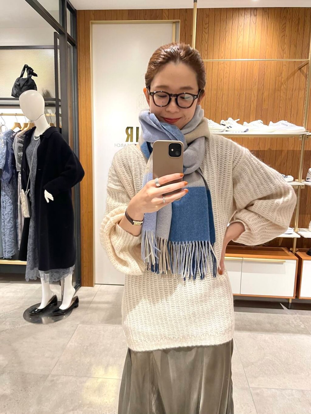 グリーン系のスカート、ホワイト系のニット/セーター、ブルー系のマフラーを着用したレディースの冬コーディネートの3枚目の写真