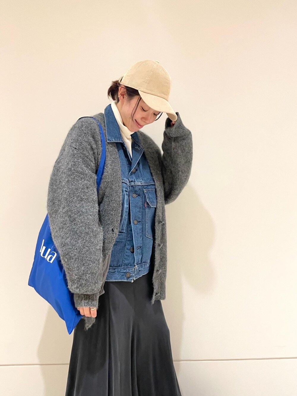 グリーン系のスカート、ブラック系のブーツ、ブルー系のデニムジャケットを着用したレディースの冬コーディネートの3枚目の写真