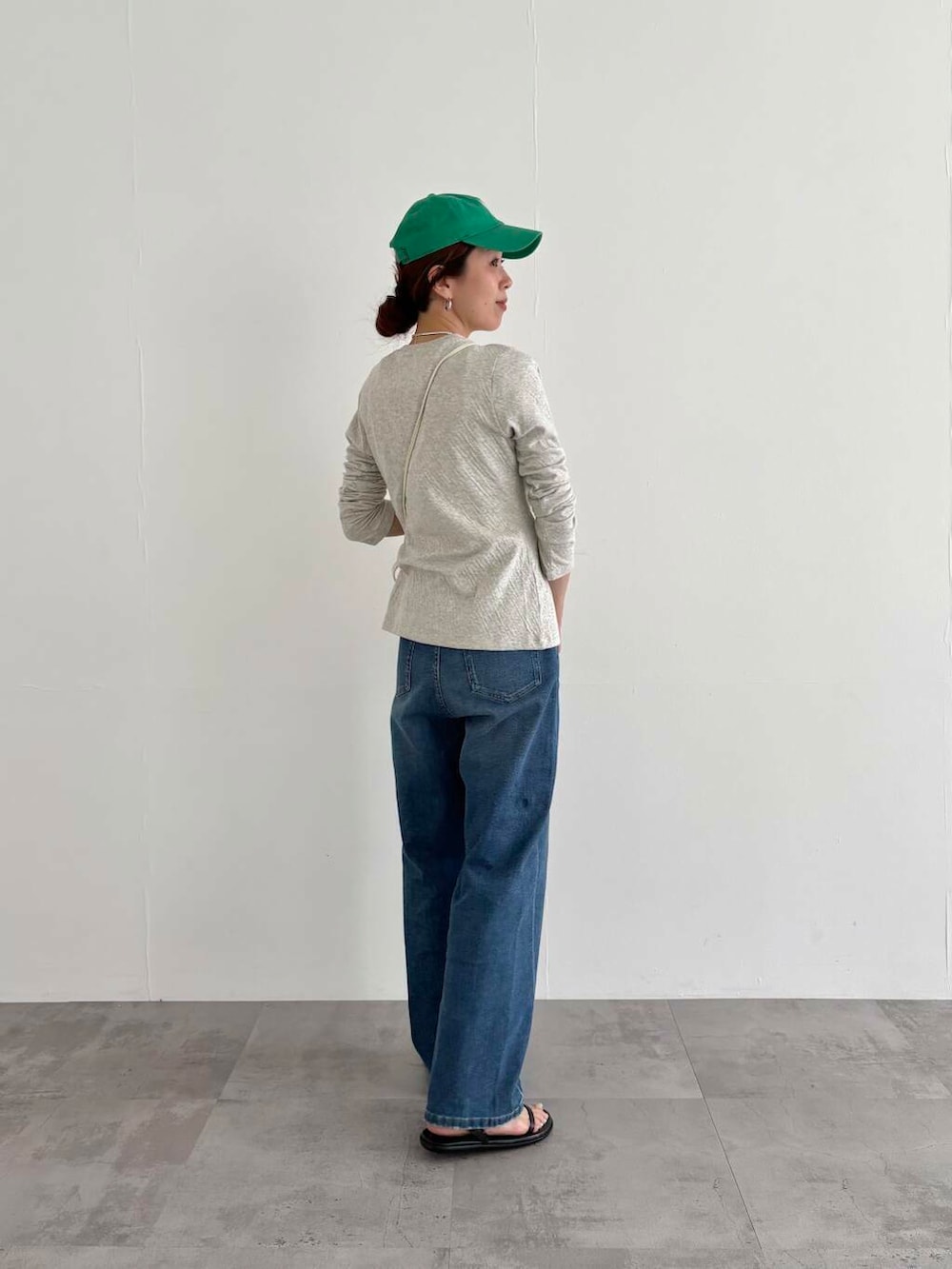 グレー系のカーディガン/ボレロ、ブルー系のデニムパンツ、ホワイト系のショルダーバッグを着用したレディースの春コーディネートの3枚目の写真