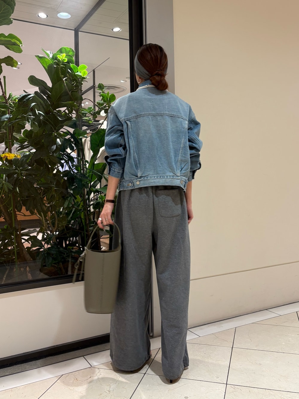 ブルー系のデニムジャケット、グリーン系のハンドバッグ、グレー系のヘアバンドを着用したレディースの春コーディネートの4枚目の写真