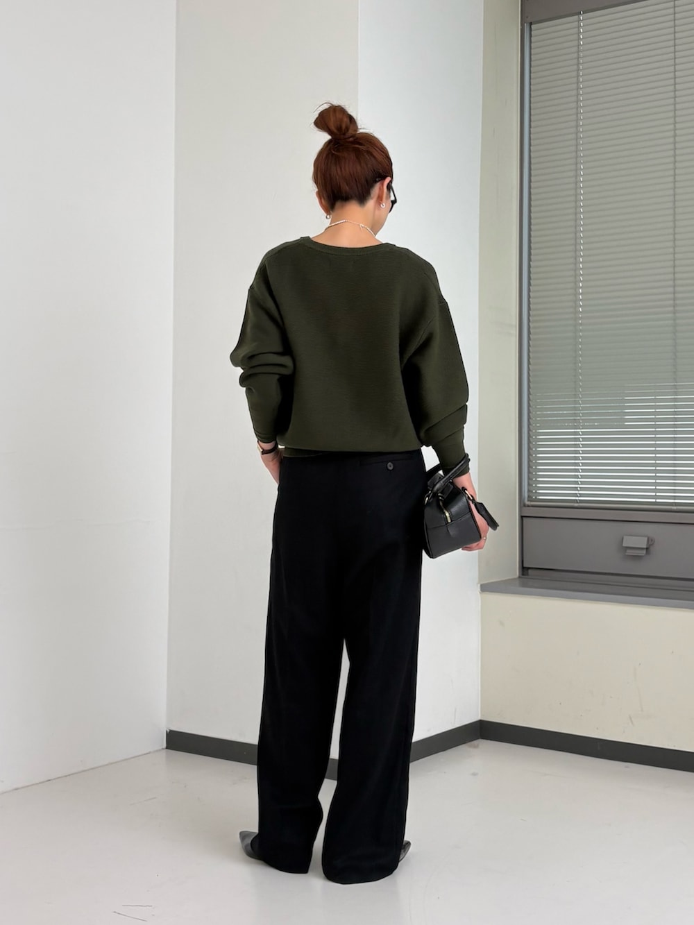 グリーン系のニット/セーター、ホワイト系のTシャツ/カットソー、ブラウン系のハンドバッグを着用したレディースの秋コーディネートの4枚目の写真