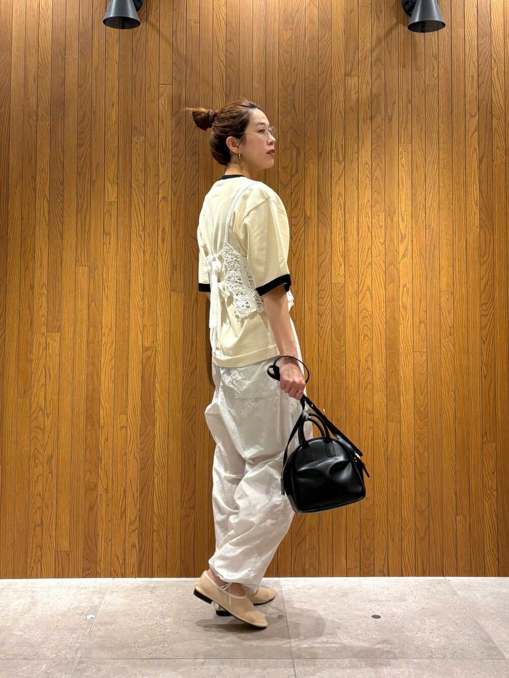 ホワイト系のニット/セーター、グレー系のその他パンツ、ブラック系のショルダーバッグを着用したレディースの夏コーディネートの3枚目の写真