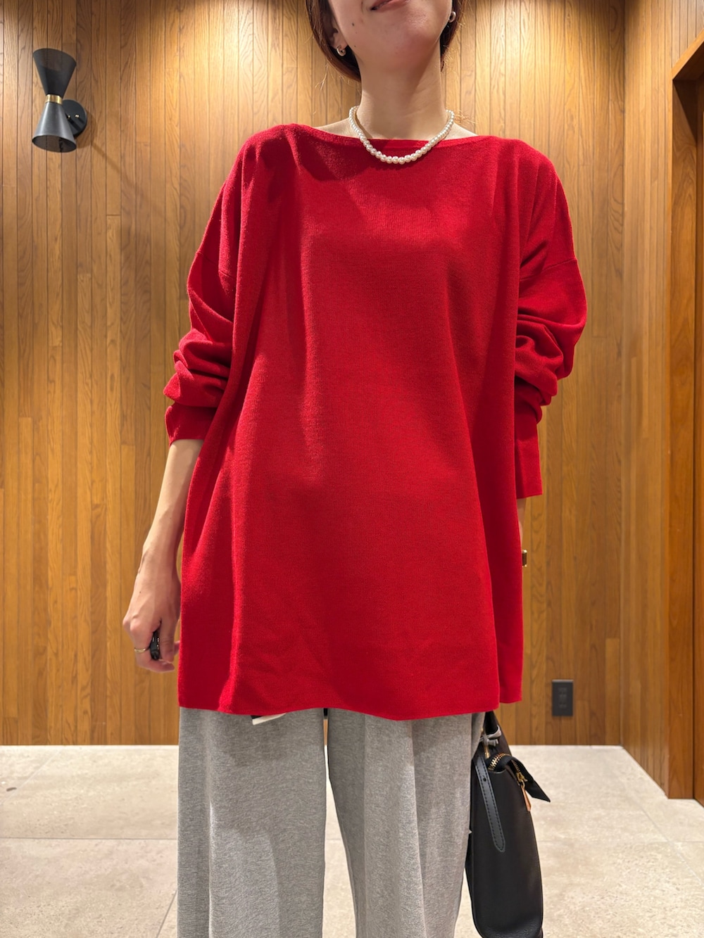 レッド系のニット/セーター、ブルー系のTシャツ/カットソー、グレー系のその他パンツを着用したレディースの秋コーディネートの7枚目の写真