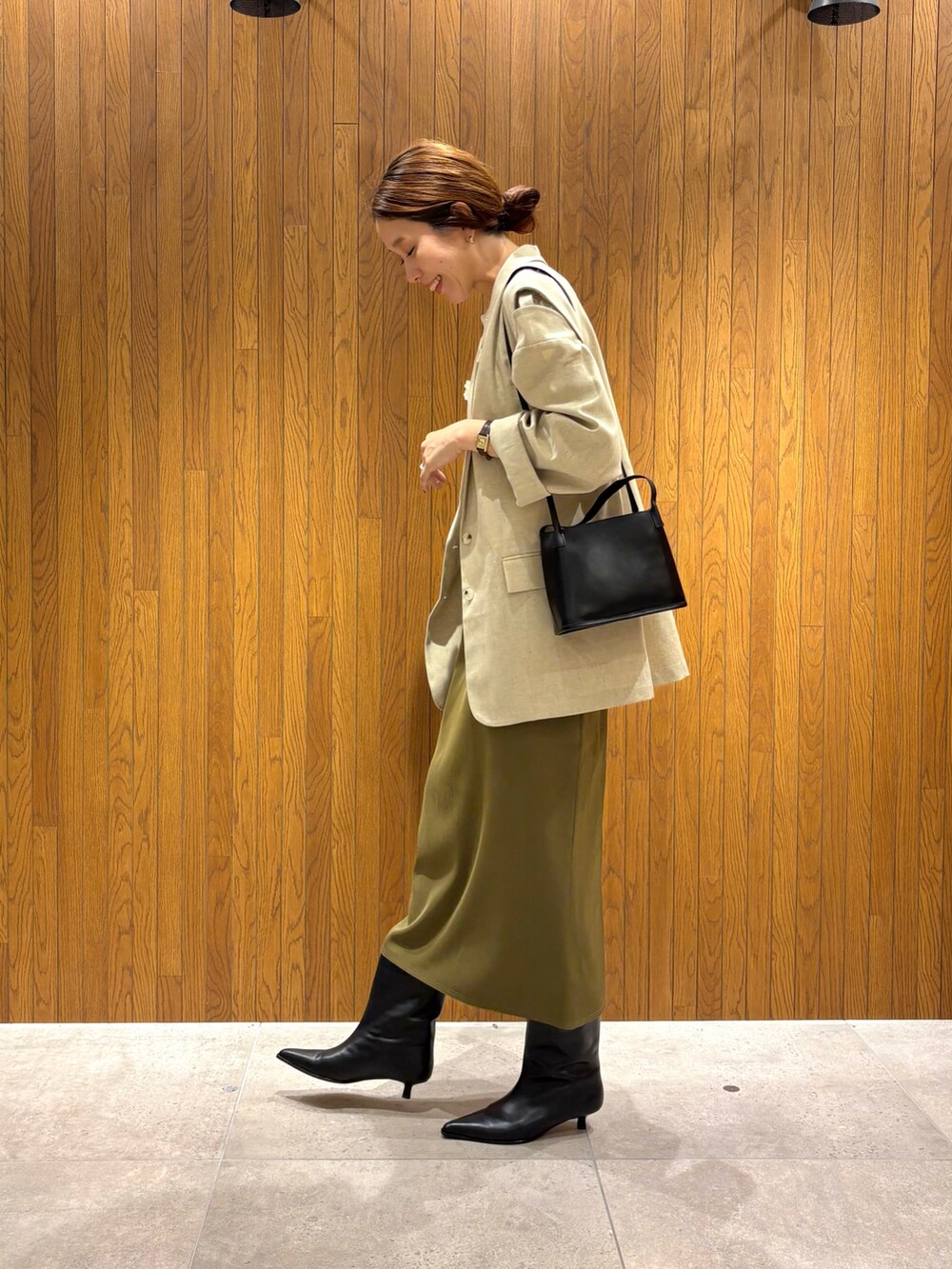 グリーン系のスカート、ブラック系のブーツ、ホワイト系のその他アウターを着用したレディースの秋コーディネートの2枚目の写真