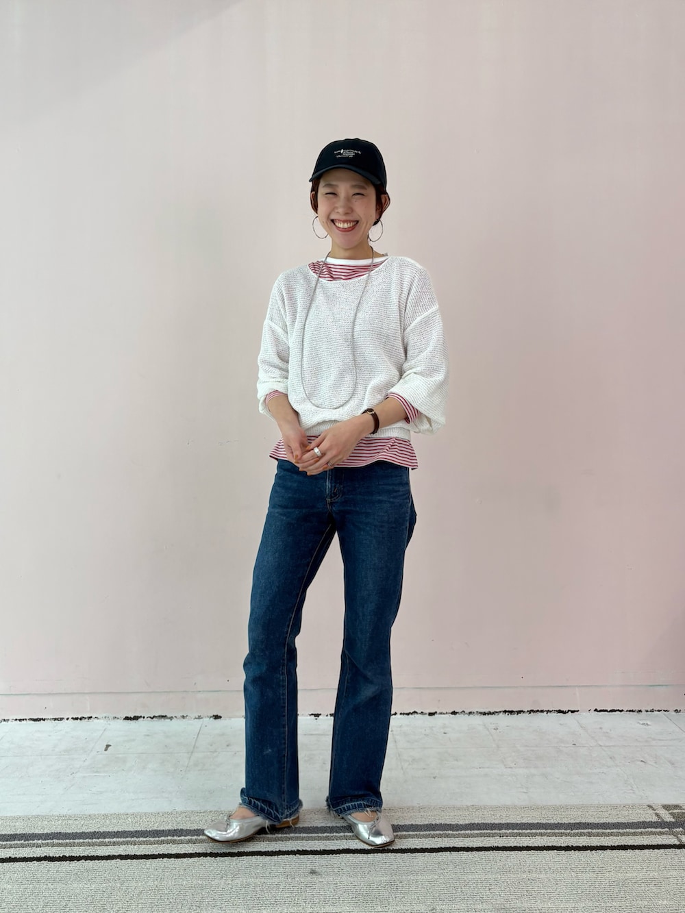 レッド系のTシャツ/カットソー、ホワイト系のニット/セーター、ブルー系のキャップを着用したレディースの春コーディネートの4枚目の写真